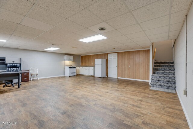 interior space featuring visible vents, stairs, freestanding refrigerator, wood finished floors, and concrete block wall