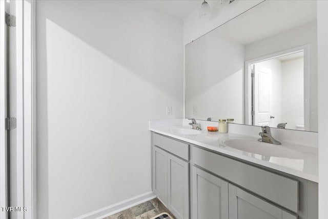 bathroom with double vanity, baseboards, and a sink