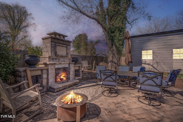 view of patio with an outdoor fire pit, an outdoor stone fireplace, and fence