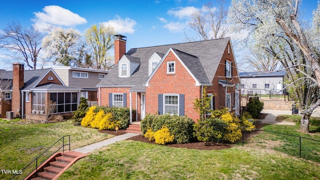 view of front facade featuring a sunroom, fence, a front yard, brick siding, and a chimney