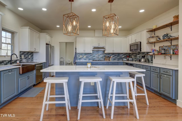 137 Unaka View Rd, Johnson City, TN 37601 - kitchen featuring a kitchen island, under cabinet range hood, appliances with stainless steel finishes, white cabinetry, and a kitchen breakfast bar