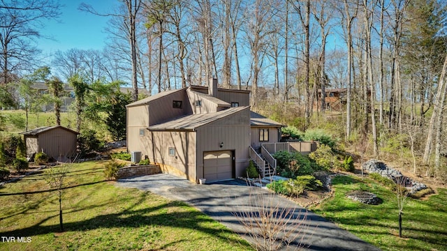 view of side of property with central air condition unit, a lawn, driveway, an outdoor structure, and a chimney