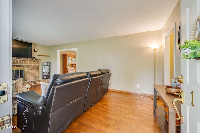living room with light wood-style flooring and a brick fireplace