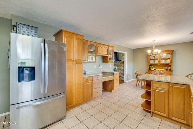 kitchen with stainless steel fridge, a textured ceiling, glass insert cabinets, open shelves, and light tile patterned floors