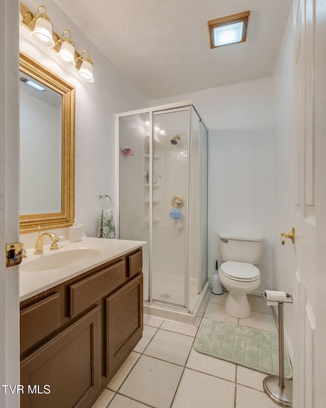 bathroom with tile patterned floors, vanity, a shower stall, and toilet