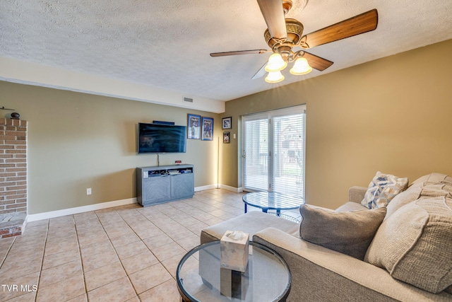 living area featuring a textured ceiling, light tile patterned floors, ceiling fan, baseboards, and visible vents