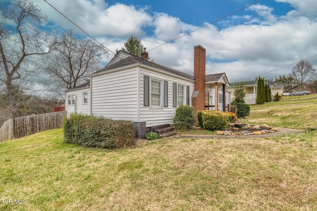 view of home's exterior featuring a yard, a chimney, and fence