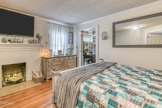 bedroom with a textured ceiling, light wood-style flooring, and ornamental molding