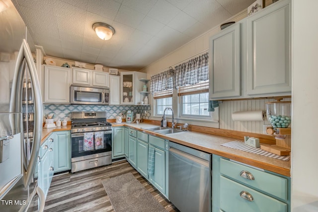 kitchen with wood finished floors, stainless steel appliances, light countertops, and a sink