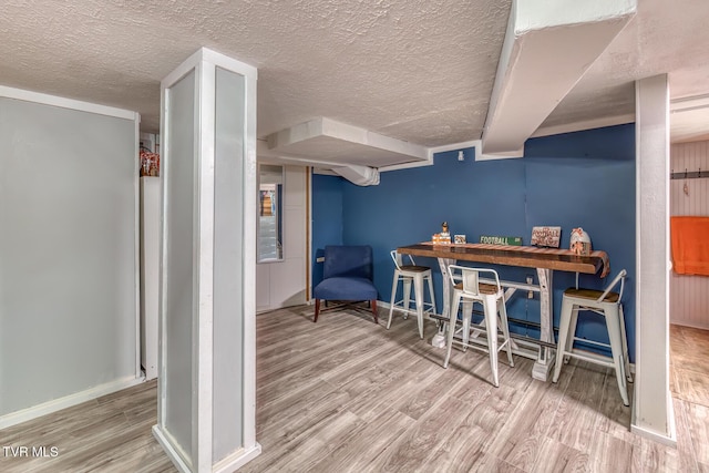 dining space featuring baseboards, a textured ceiling, and wood finished floors