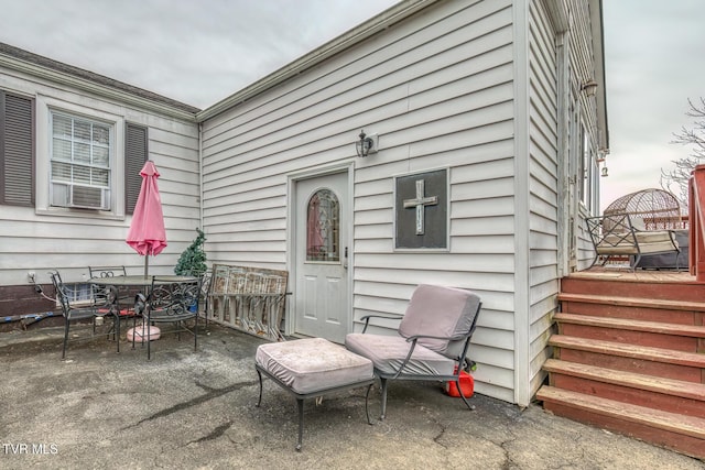 doorway to property featuring outdoor dining area, a patio area, and cooling unit