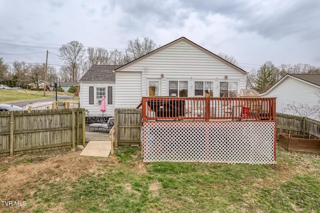 back of property featuring a yard, roof with shingles, a deck, and fence