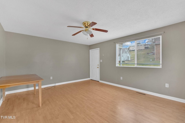 spare room featuring light wood-style flooring, baseboards, and a ceiling fan