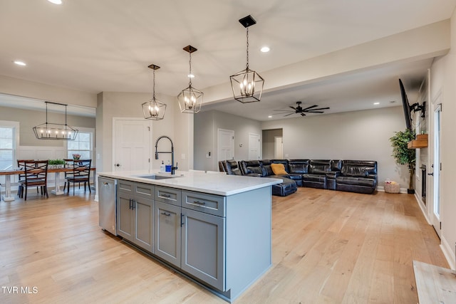 kitchen with light wood-type flooring, gray cabinetry, a sink, stainless steel dishwasher, and ceiling fan