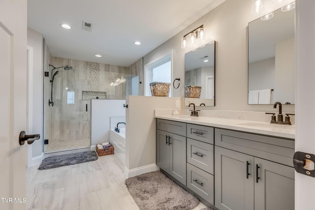 full bathroom featuring visible vents, a shower stall, a garden tub, double vanity, and a sink