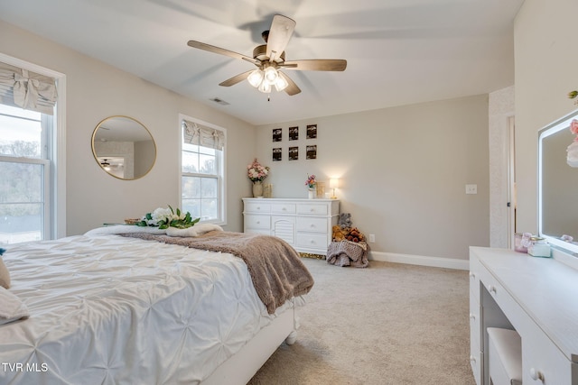 bedroom with baseboards, light carpet, visible vents, and ceiling fan