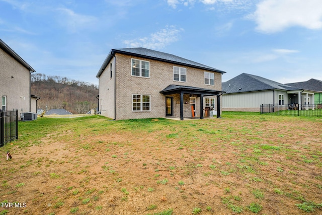 rear view of property with a patio, central AC, fence, a yard, and brick siding