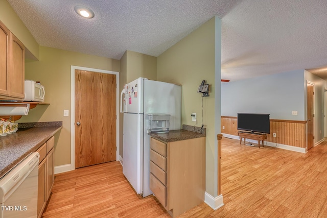 kitchen with dark countertops, a textured ceiling, white appliances, and light wood-style flooring