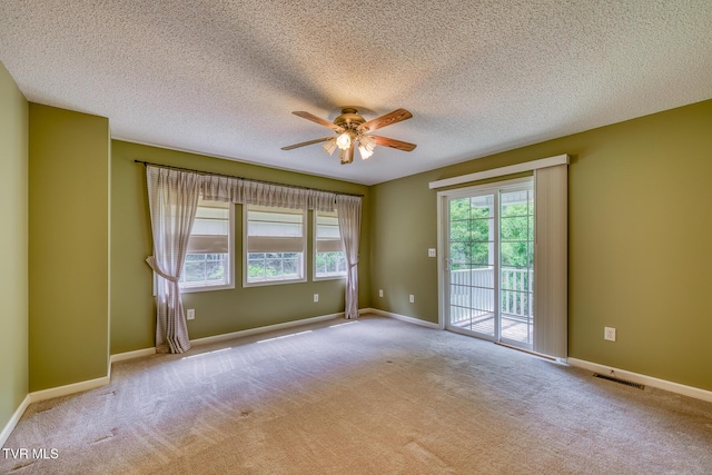 empty room featuring ceiling fan, carpet floors, a healthy amount of sunlight, and a textured ceiling