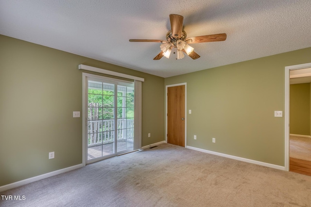 carpeted spare room featuring a textured ceiling, a ceiling fan, and baseboards
