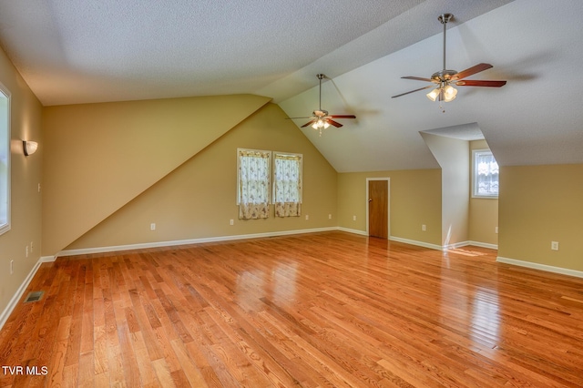 bonus room featuring ceiling fan, light wood finished floors, baseboards, lofted ceiling, and visible vents