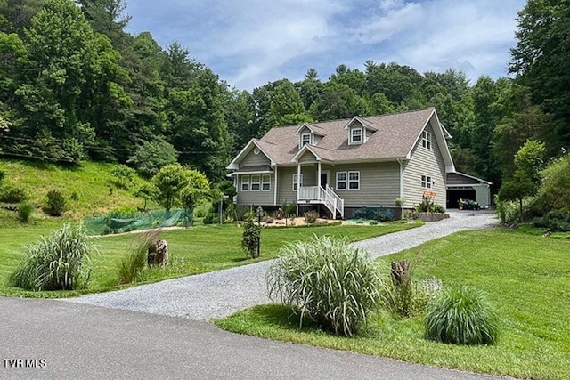 cape cod home featuring gravel driveway, a view of trees, and a front yard