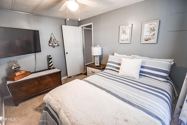 bedroom with light colored carpet, a ceiling fan, and a decorative wall
