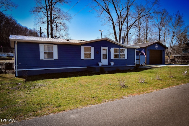 view of front of home featuring a garage, driveway, metal roof, and a front lawn
