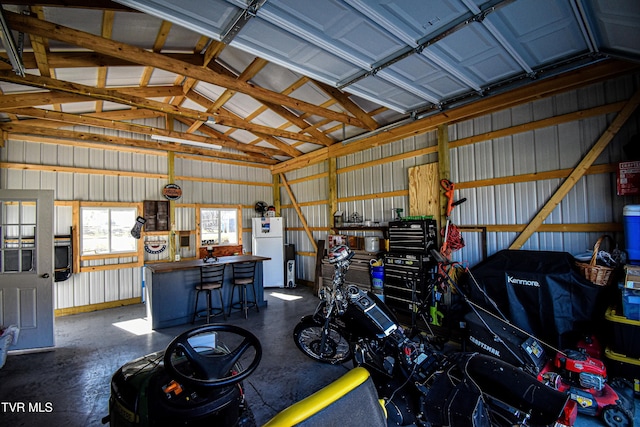 garage featuring metal wall and freestanding refrigerator