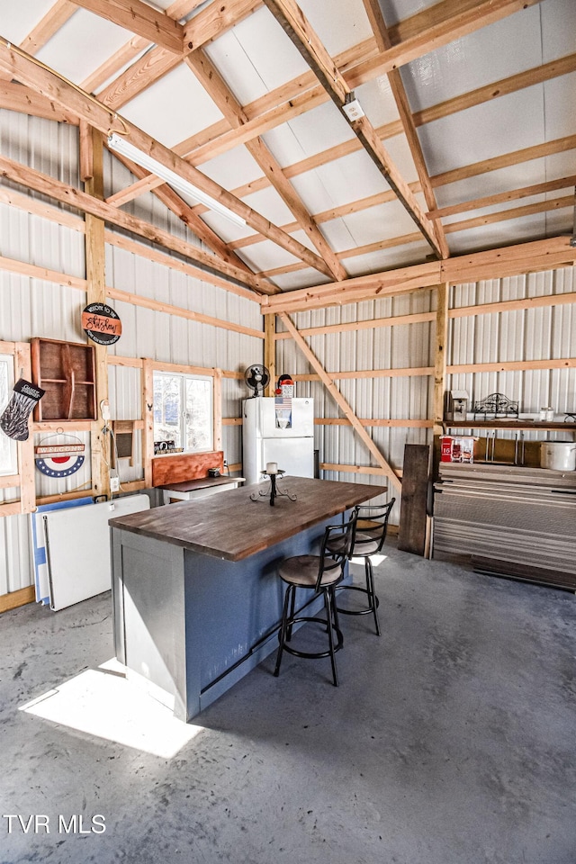 garage featuring metal wall and freestanding refrigerator