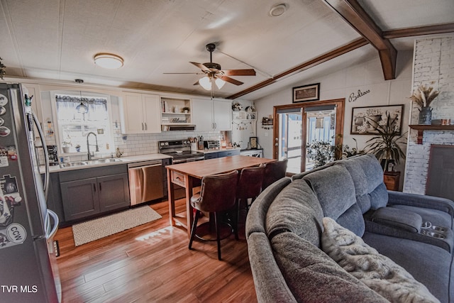 kitchen featuring open floor plan, plenty of natural light, appliances with stainless steel finishes, and a sink