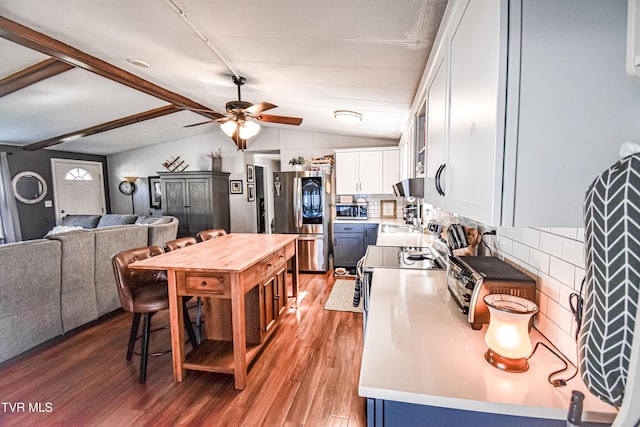 kitchen featuring vaulted ceiling with beams, light wood-style flooring, appliances with stainless steel finishes, white cabinets, and a ceiling fan