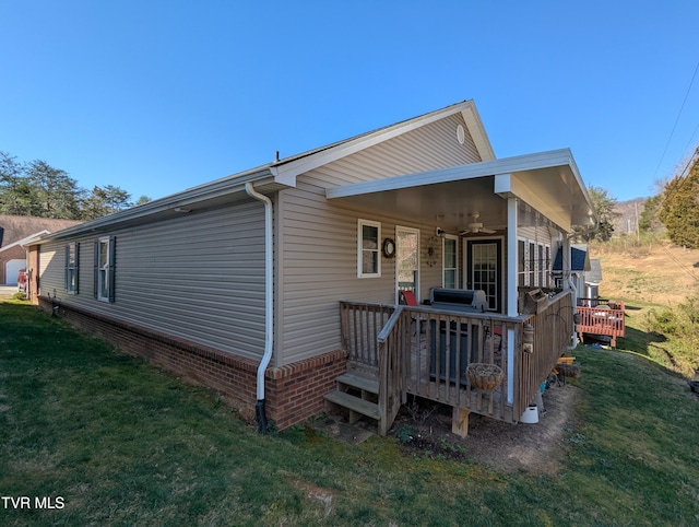 exterior space with a ceiling fan, a lawn, and a wooden deck