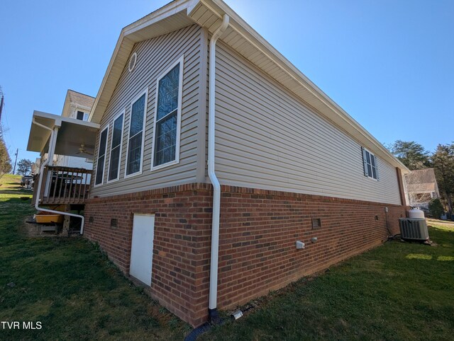 view of home's exterior with a ceiling fan, cooling unit, a lawn, and brick siding