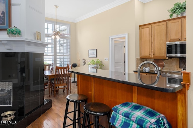 20324 Josh Allen Dr, Abingdon, VA 24211 - kitchen with a ceiling fan, stainless steel microwave, a kitchen breakfast bar, backsplash, and crown molding