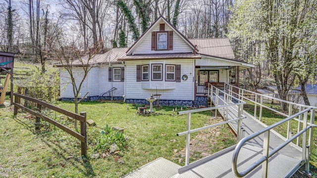 chalet / cabin with a porch, a front yard, stairs, and metal roof
