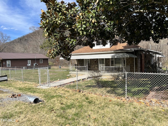 view of front of house featuring a front lawn, a shingled roof, stone siding, and fence private yard