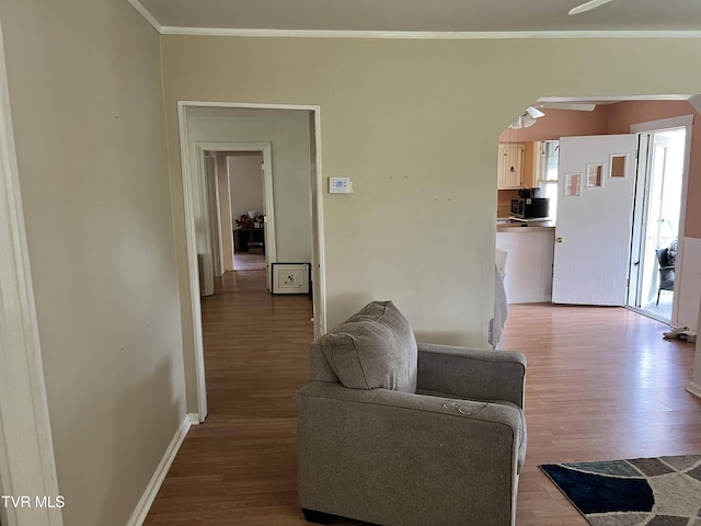 living room featuring a ceiling fan, ornamental molding, a healthy amount of sunlight, and wood finished floors