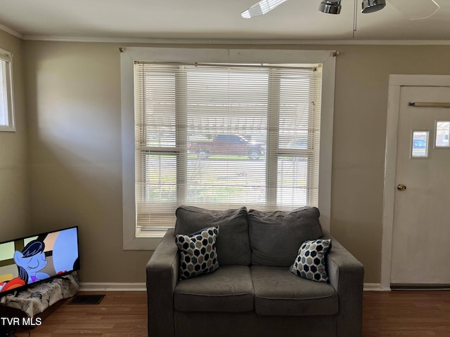 living room with ornamental molding, baseboards, visible vents, a ceiling fan, and wood finished floors