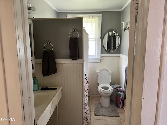 bathroom featuring crown molding, toilet, tile patterned flooring, and wainscoting