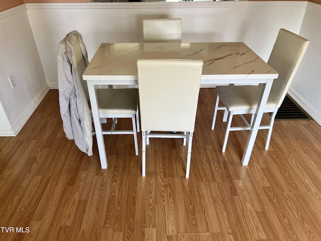 unfurnished dining area featuring baseboards and wood finished floors