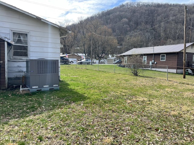 view of yard with central AC and fence