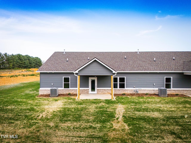 back of house with central AC, a patio, roof with shingles, and a lawn