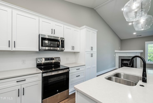 kitchen with stainless steel appliances, vaulted ceiling, a sink, light countertops, and backsplash