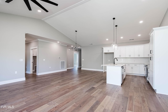 kitchen with a ceiling fan, vaulted ceiling, open floor plan, backsplash, and light countertops