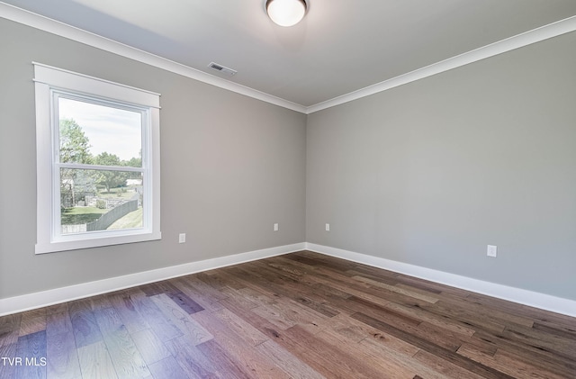 empty room featuring crown molding, dark wood finished floors, and baseboards