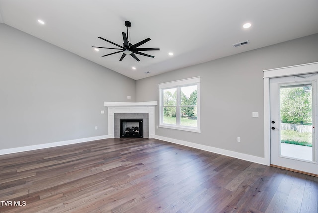 unfurnished living room with healthy amount of natural light, vaulted ceiling, a ceiling fan, dark wood finished floors, and a fireplace