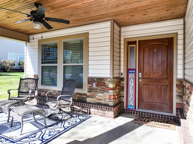 doorway to property with stone siding, a porch, and ceiling fan