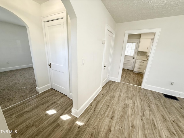 unfurnished bedroom with visible vents, arched walkways, and wood finished floors