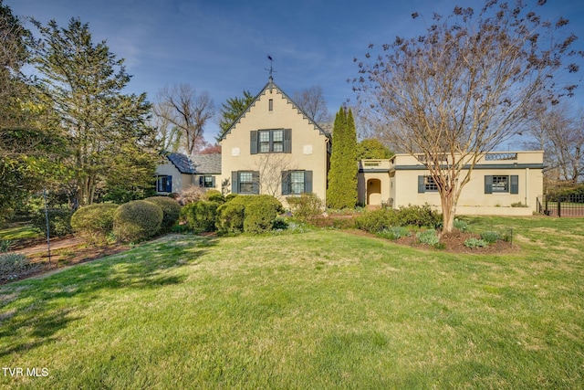 view of front of home featuring a front lawn, stucco siding, and fence
